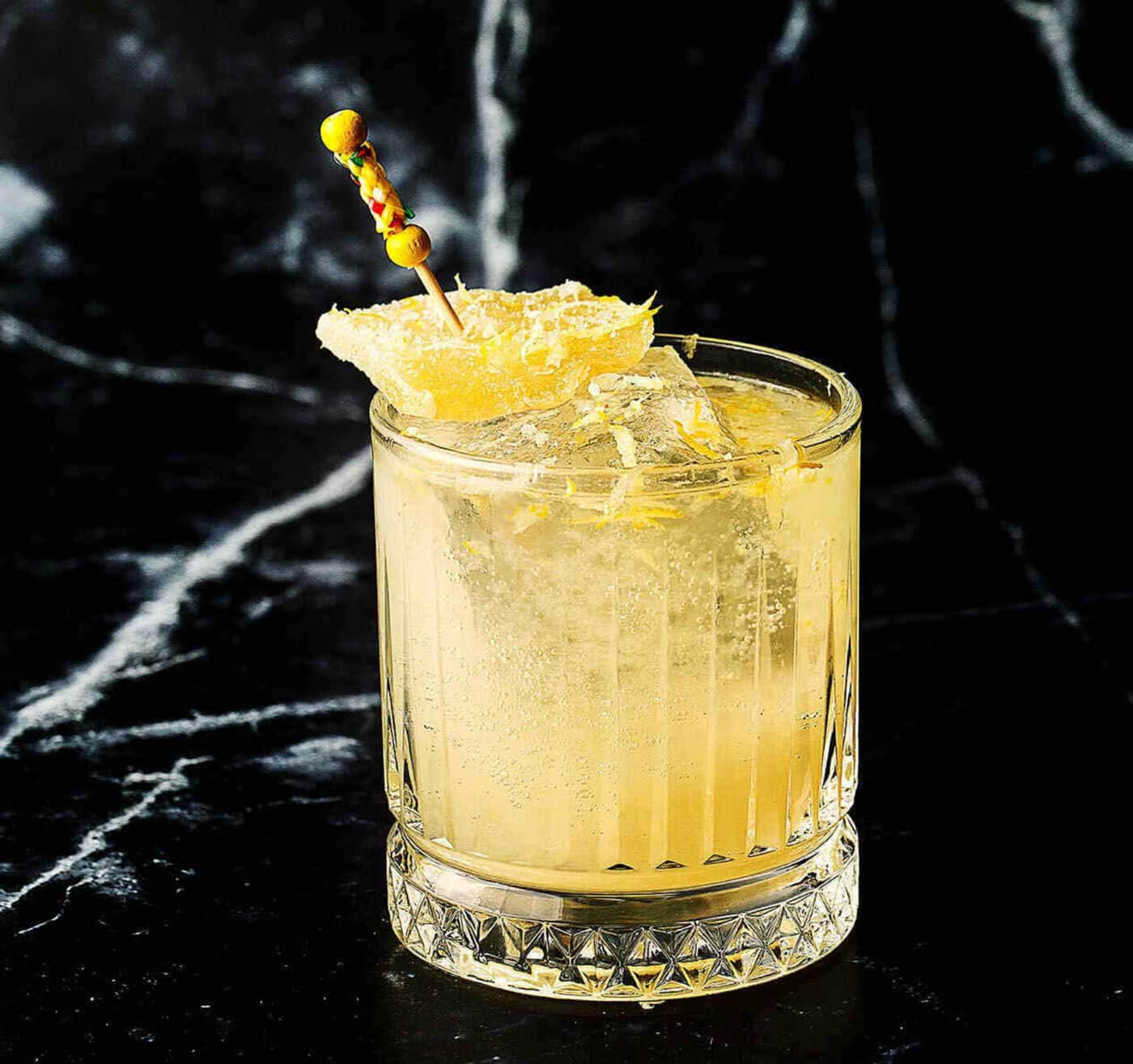 Yellow drink in a crystal glass with a black marbled background